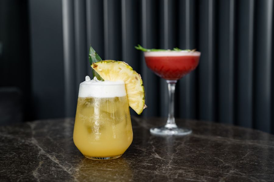 Two bright cocktails on a marble bar