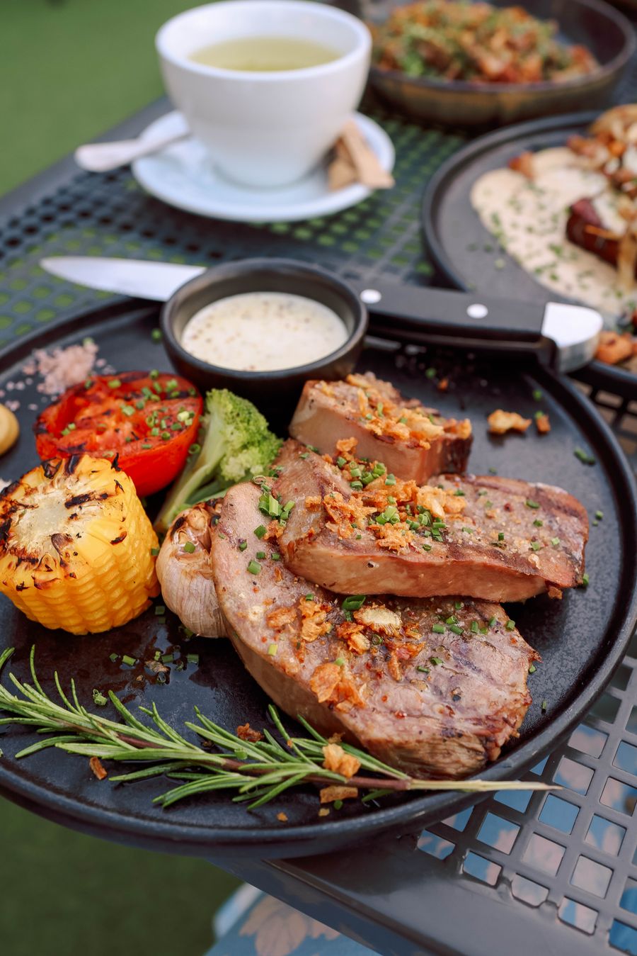 A mixed grill of meats and vegetables on a dark tray