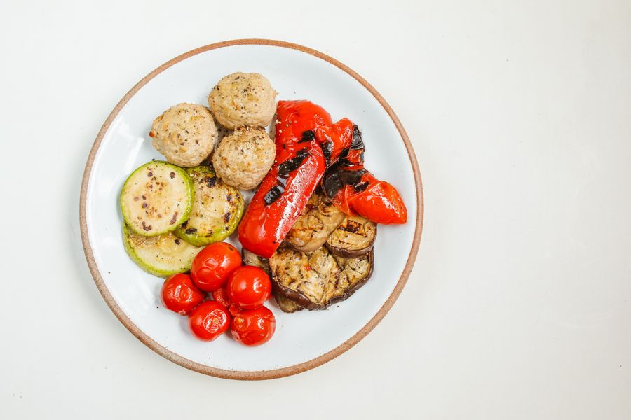 Seared scallops with vegetables on a white plate