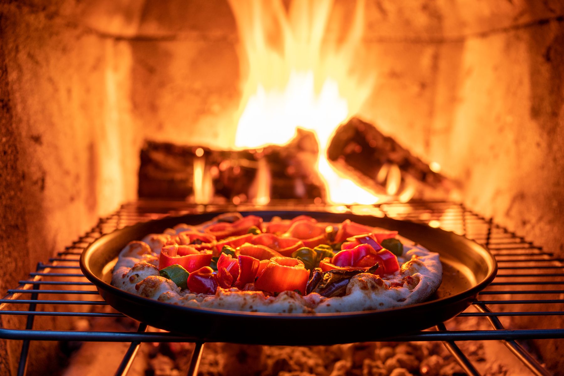 Vegetables roasting in a wide pan over an open wood fire