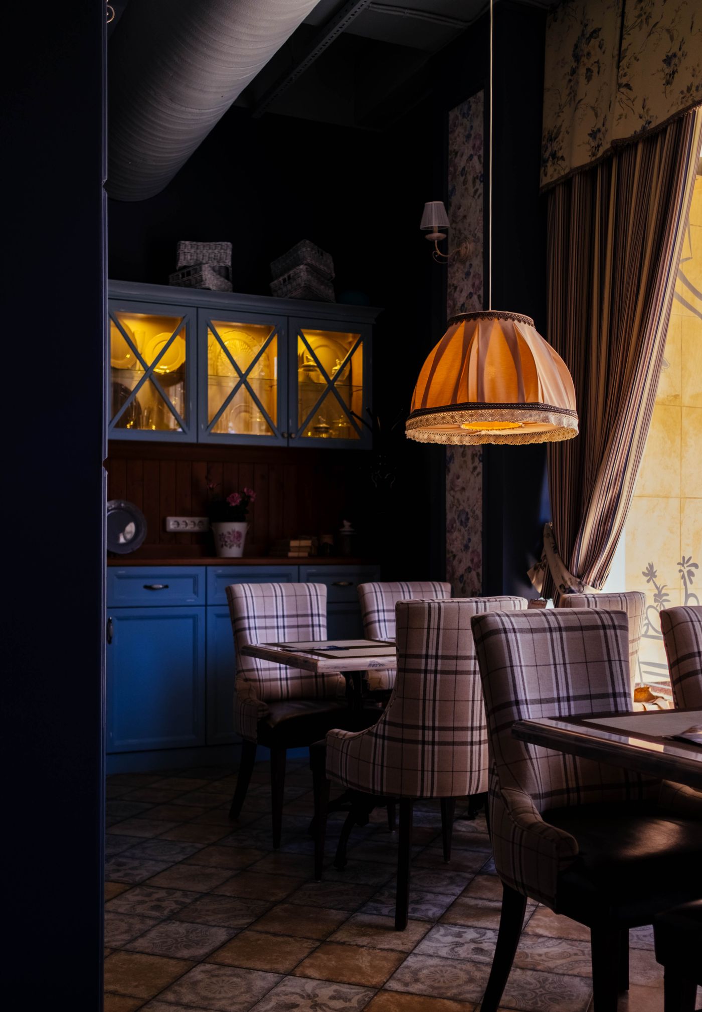 A dark dining room with pendant lamps and upholstered chairs